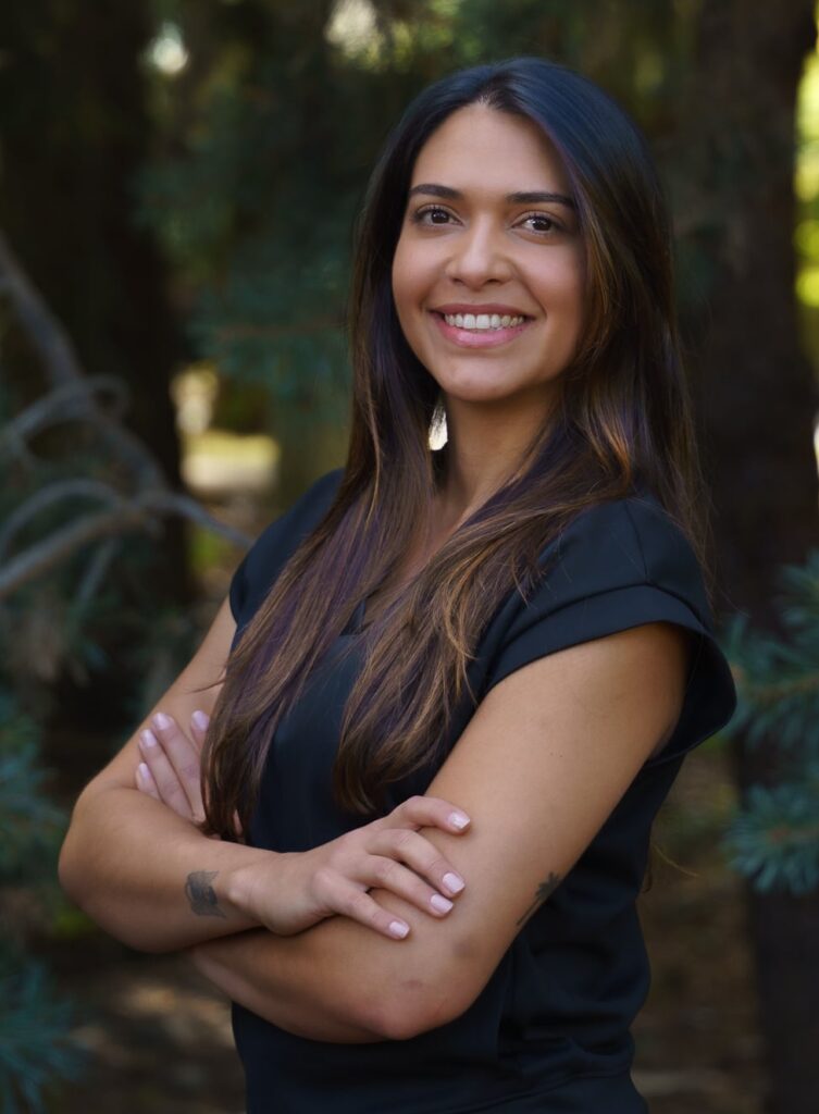 An image of Dr. Natalia, a female chiropractor, standing with her arms crossed and smiling.