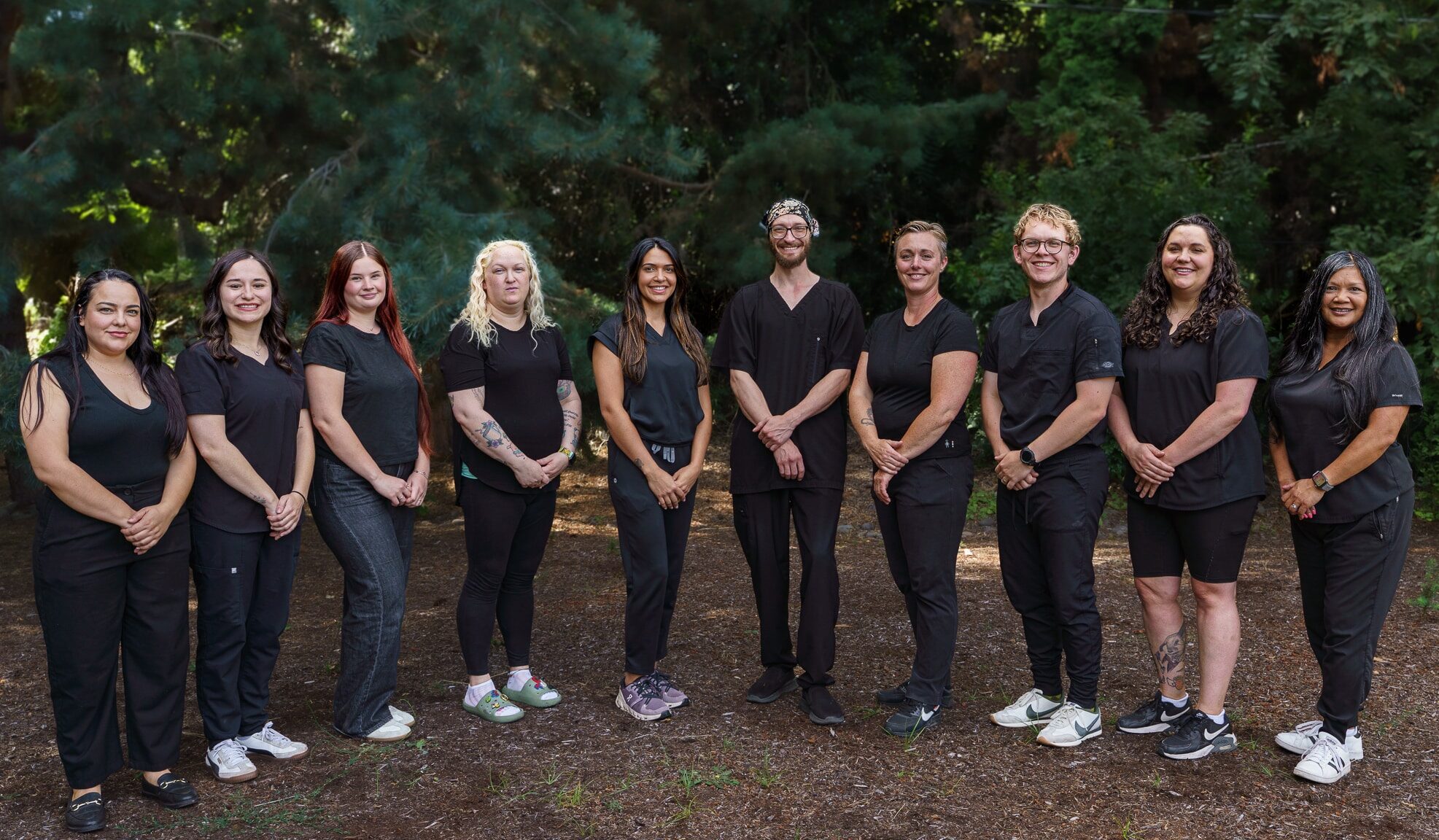 An image of ten people, all wearing black clothes, standing in a line and smiling at the camera.